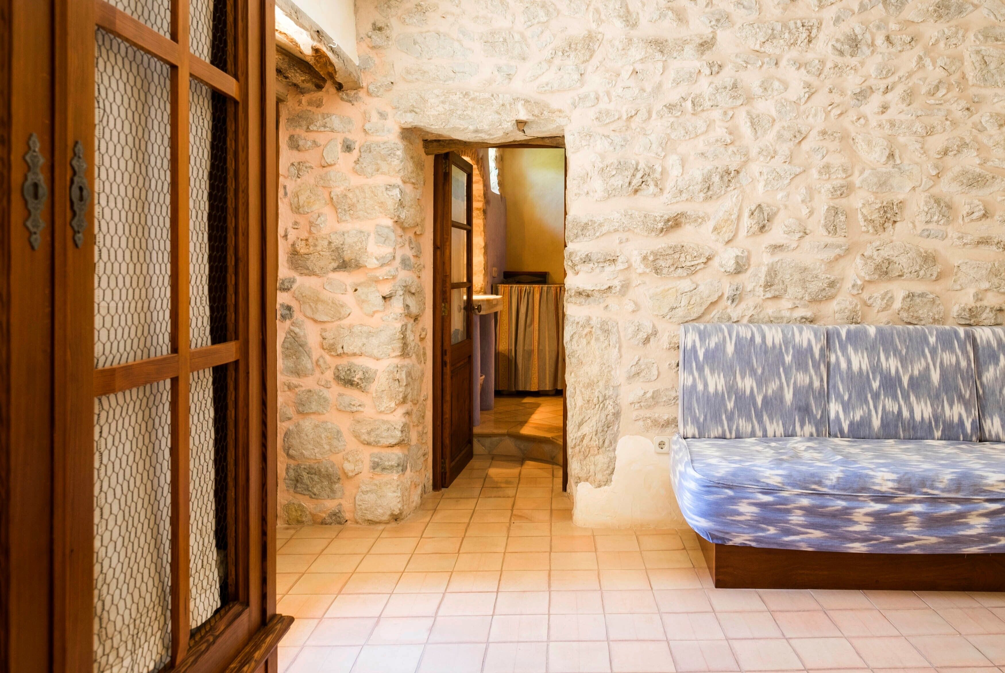 A stone-walled corridor leading to a room with a patterned sofa.