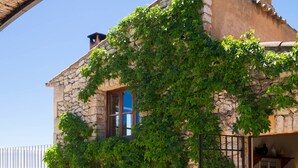 A stone building with a balcony, a barbecue grill, and a wooden table. - Natural Stone Villa with Pool: Villa Son Reus (Felanitx)