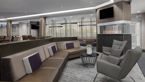Un área de descanso moderna con un amplio sofá modular, un sillón estampado y una pequeña mesa redonda.