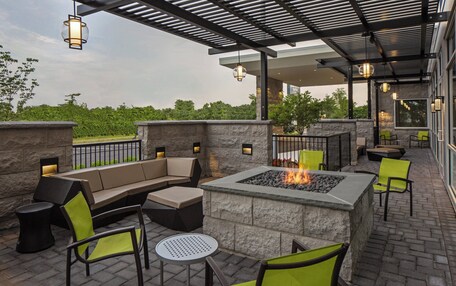 An outdoor patio with a stone fire pit, seating areas, and ambient lighting.
