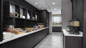 Una cocina moderna con armarios oscuros, una encimera amplia y diversos productos alimenticios.