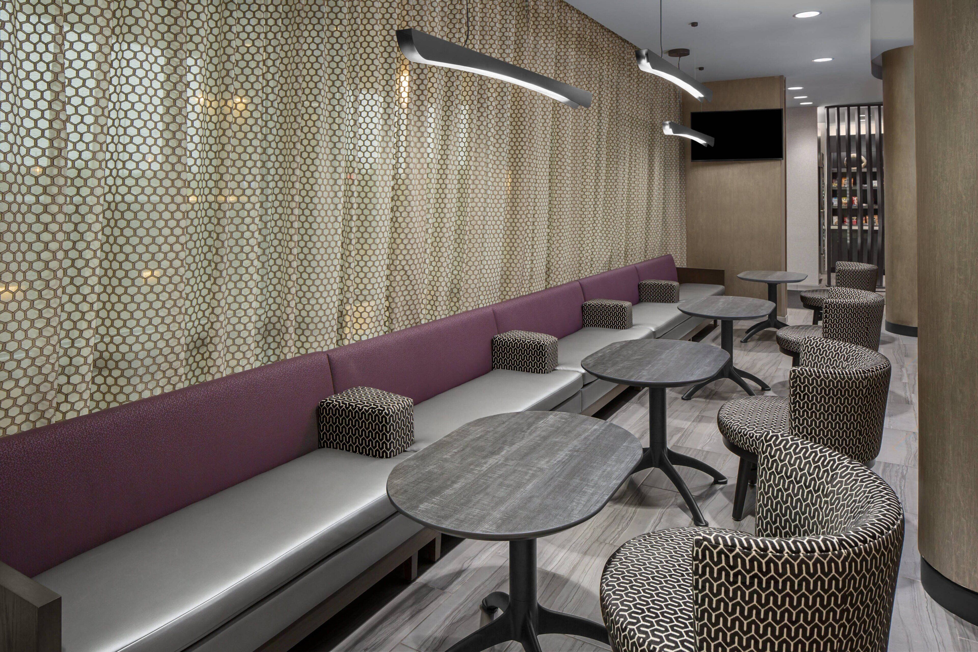 A modern interior with seating areas, tables, and a patterned wall.
