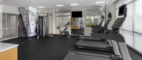Un gimnasio moderno con cintas de correr, bicicletas estáticas y máquinas de pesas.