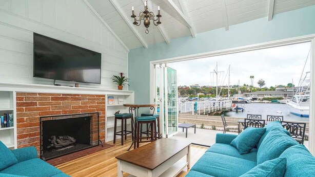 A living room with a fireplace, a television, and a view of a marina.