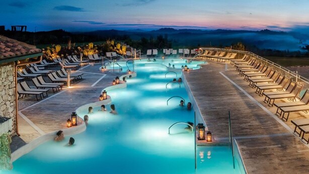A pool area with lounge chairs and a view of the mountains.