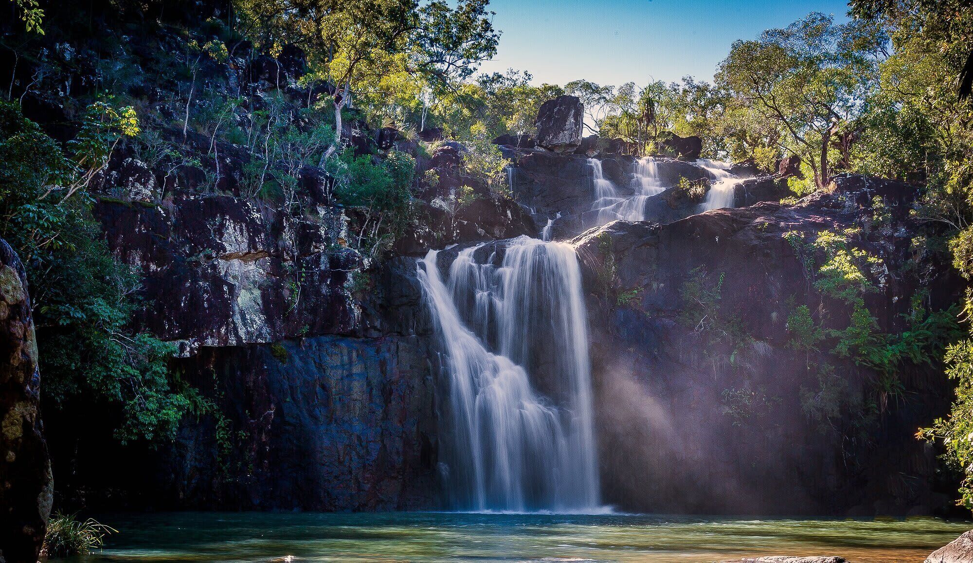 Een waterval omringd door dicht bos.