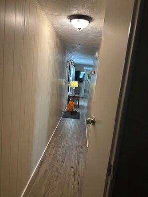 A narrow hallway with wooden flooring, a ceiling light, and a door on the right. - Rainbow River Experience. (Dunnellon)