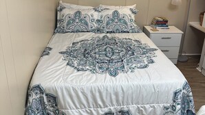 A bedroom with a bed, a bedside table with books, a wall art piece, and a floor lamp. - Rainbow River Experience. (Dunnellon)