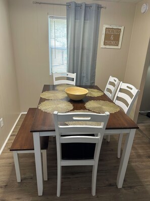 A dining area with a wooden table, white chairs, and a decorative bowl centerpiece.