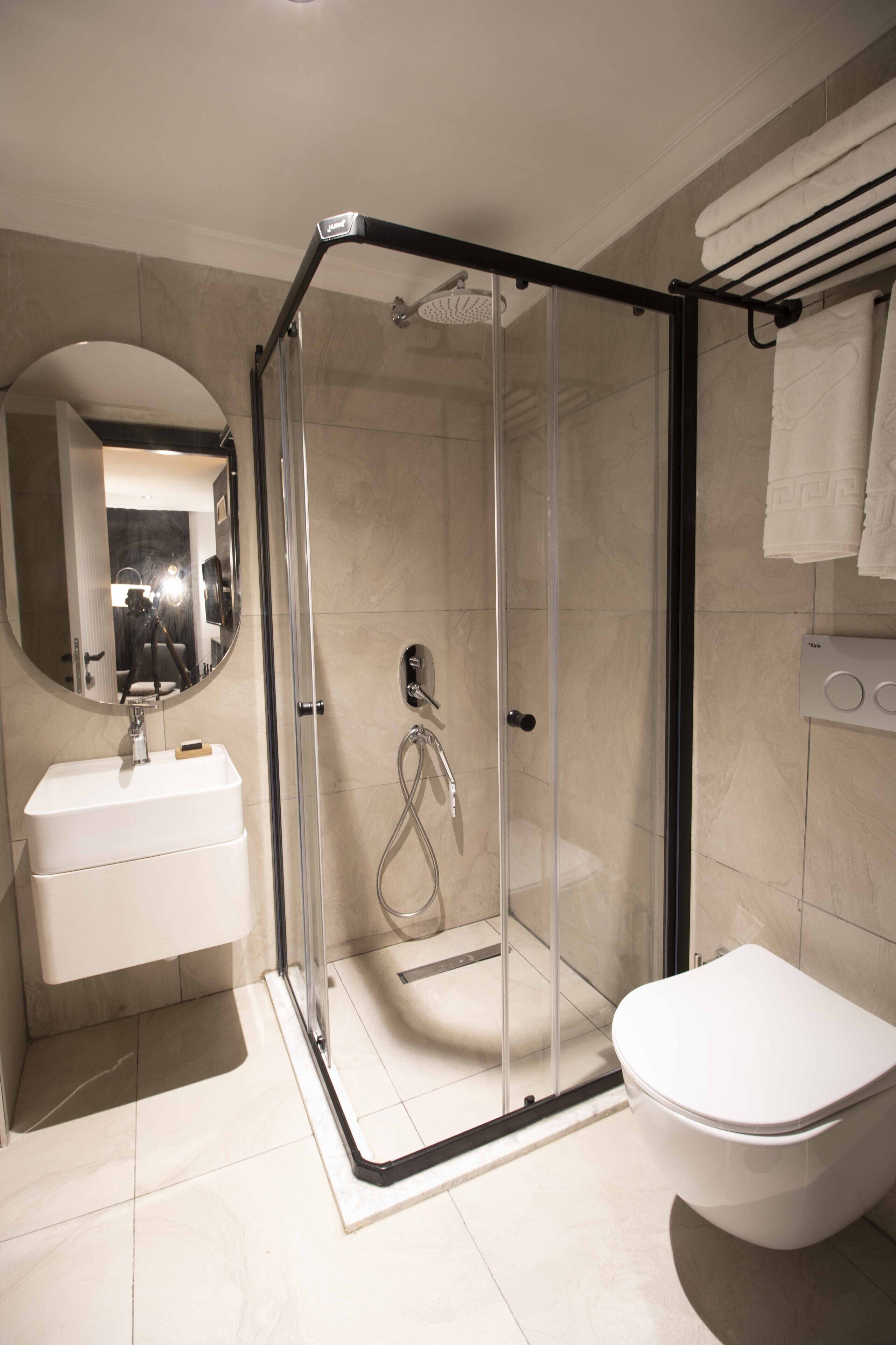 Un baño moderno con ducha envuelta en vidrio, un lavabo blanco y un inodoro.