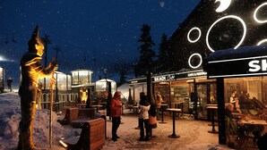 Een besneeuwde buitenruimte met een standbeeld, houten banken en een gebouw met verlichte borden.