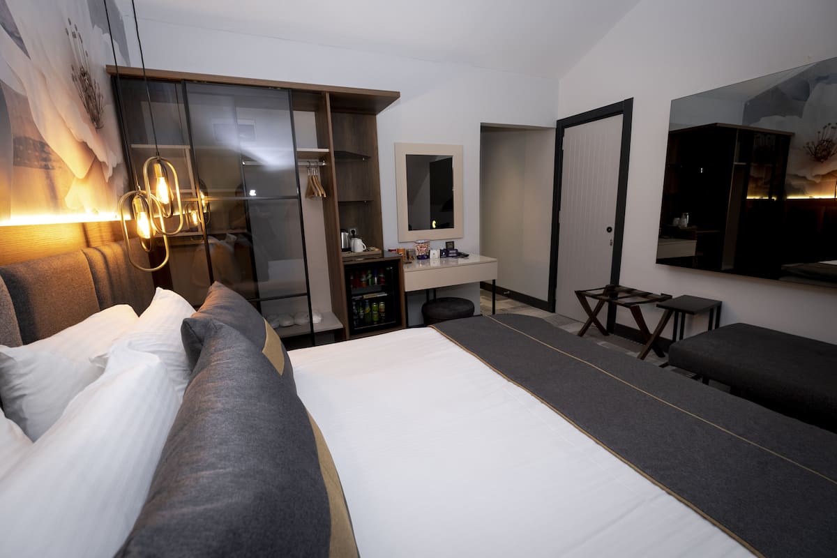 Ein modernes Hotelzimmer mit einem großen Bett, einem Schreibtisch, einem Kleiderschrank und einem Spiegel.
