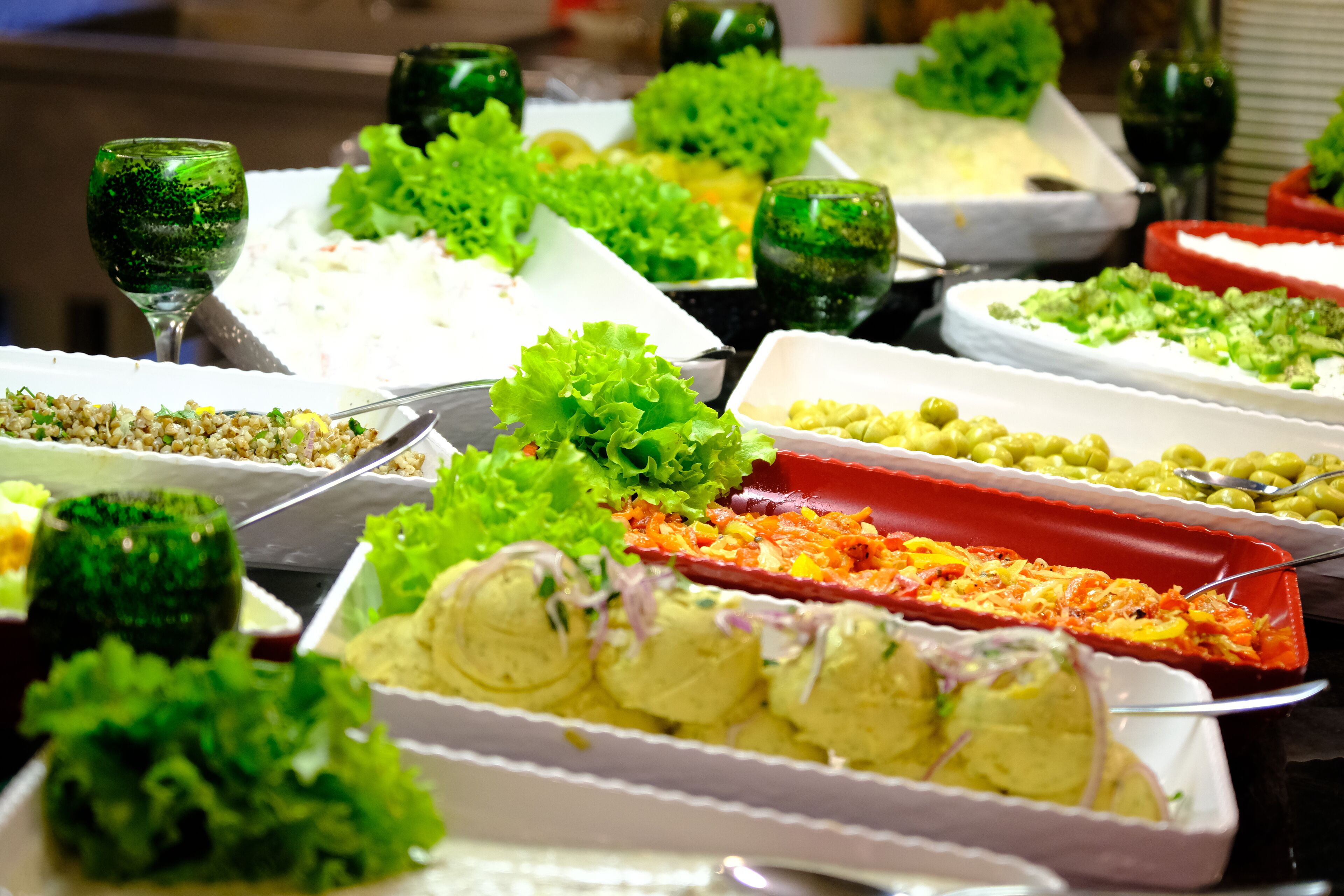 Un bufé con diversos alimentos y vasos de vidrio verde.