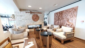 Een moderne lounge met een stenen muur, een open haard en een groot bronzen beeldhouwwerk.