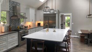 A modern kitchen with a large island, white cabinetry, and a skylight. - Vintage, restored home w/ pool, hot tub & courtyard-just blocks to town & beach (New Buffalo)
