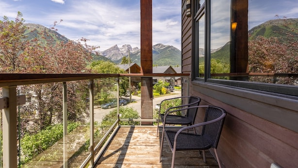 A balcony with two chairs, overlooking a mountain landscape and a residential area. - 901 Luxury Condos l Dog Friendly (Fernie)