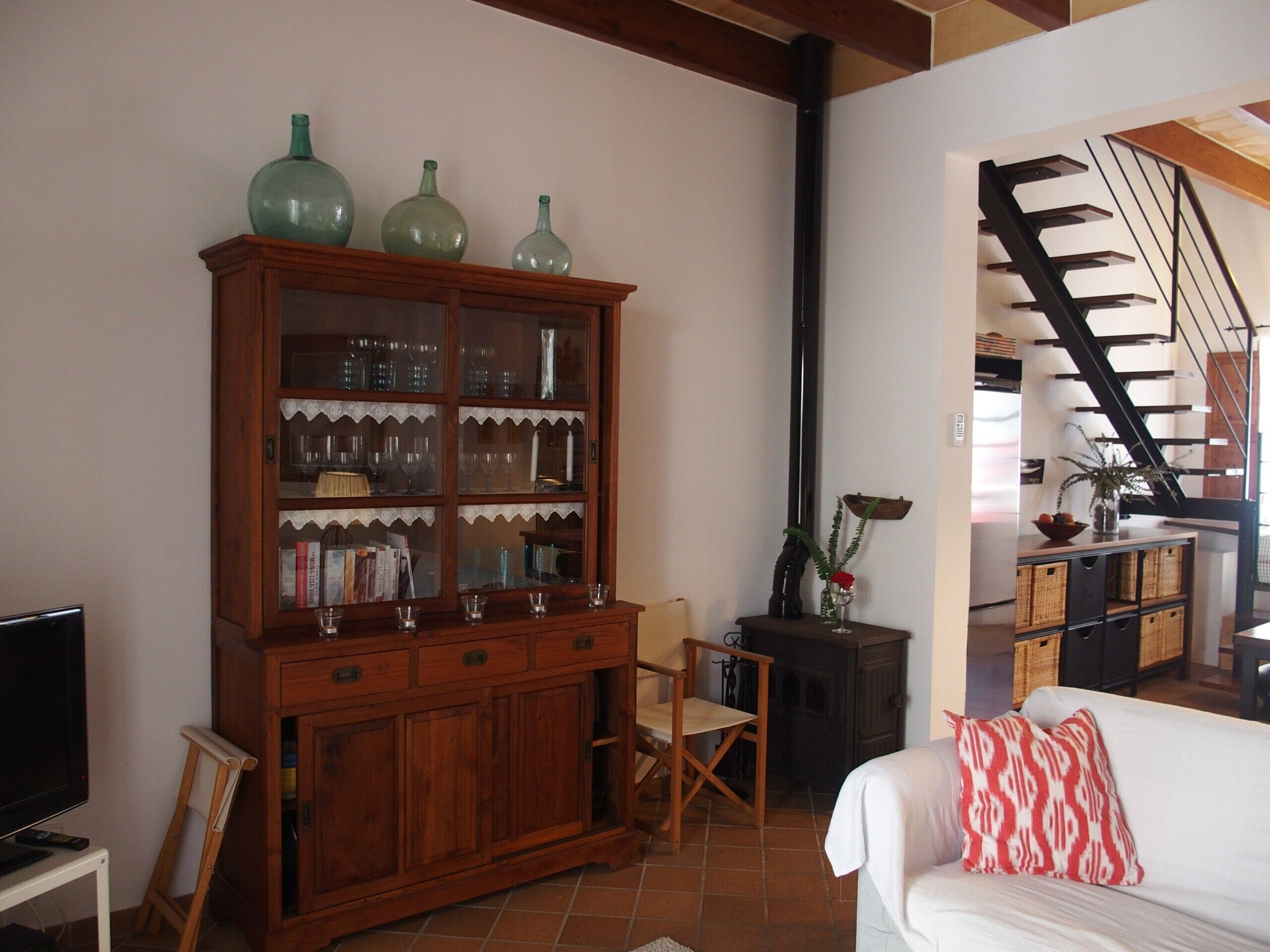 A living room with a wooden cabinet, a white sofa, a television, and a staircase.