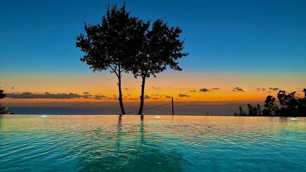 Una piscina infinita con agua cristalina y vistas al atardecer.