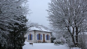 Een huis bedekt met sneeuw, met een veranda, een bankje en een kleine tafel.