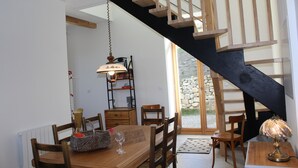 Een eethoek met een houten tafel, stoelen, een lamp en een trap.