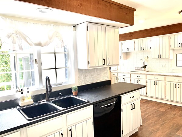 A kitchen with white cabinets, a black countertop, and a dishwasher. - Farmhouse on Alpaca Farm (located along the Canandaigua Wine Trail) (Canandaigua)