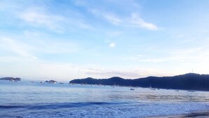 A beach with calm waters and boats.