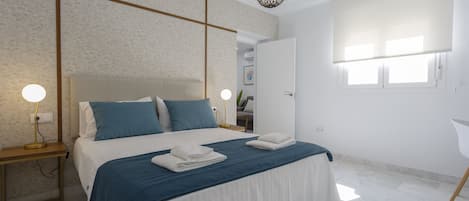 A modern bedroom with a large bed, bedside tables, and a ceiling light fixture.