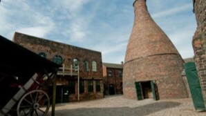 A courtyard with a brick building and a large chimney. - Townhouse @ 50 Birks Street Stoke (Stoke-on-Trent)