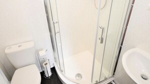 A small, modern bathroom with a glass shower enclosure, a toilet, and a sink. - Townhouse @ 50 Birks Street Stoke (Stoke-on-Trent)