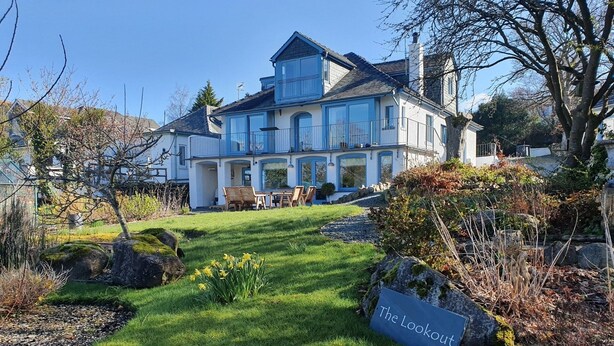 A large, multi-story house with a well-maintained lawn and a sign reading "The Lookout".