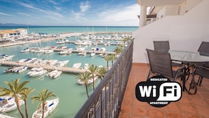 A balcony with a view of a marina filled with boats, a table, and chairs.