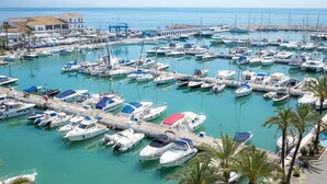 A marina with numerous boats docked, a pier, and a building with a sign.