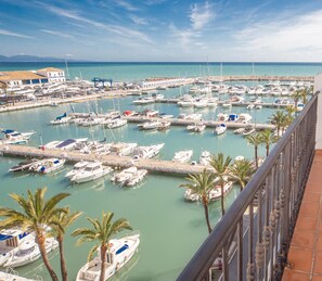 Un balcon donnant sur une marina où sont amarrés de nombreux bateaux, avec une table et des chaises.