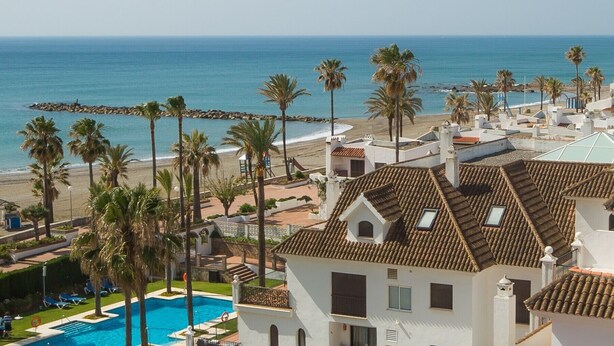 Een resort met een zwembad, toegang tot het strand en palmbomen.