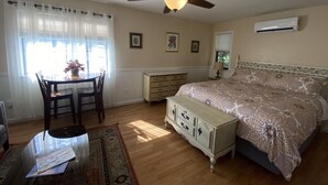 A bedroom with a bed, a dresser, a desk with chairs, a ceiling fan, and an air conditioning unit. - Spacious room with private entrance near Bidwell Park! (Chico)