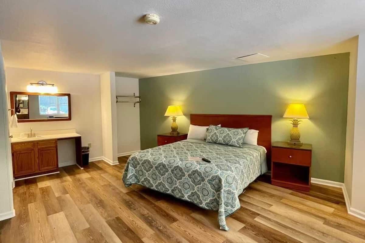 A bedroom with a bed, two bedside tables with lamps, a nightstand, a dresser, and a mirror.