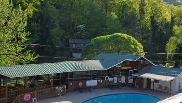 A pool area with a wooden deck, lounge chairs, and a building with a green roof.