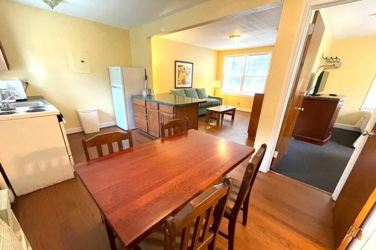 A compact kitchen with a wooden table and chairs, a refrigerator, and a small dining area.