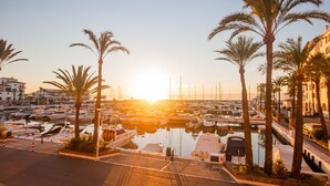 A marina with boats docked, surrounded by palm trees and buildings. - Marina Real apto 211 (Manilva)