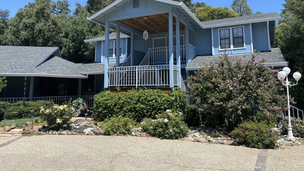 A two-story house with a covered porch and a small garden area.