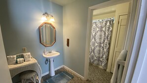A bathroom with a sink, mirror, and patterned shower curtain.