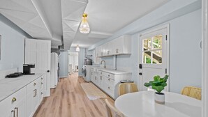 Una cucina moderna con mobili bianchi, un'area pranzo con un tavolo rotondo e una vista dalla finestra.