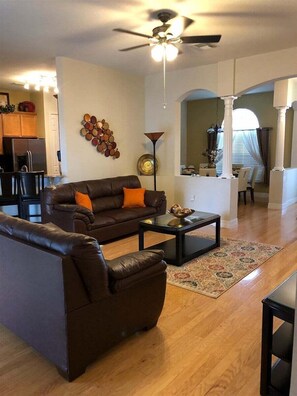 A living room with a brown leather sofa, a coffee table, and a ceiling fan.