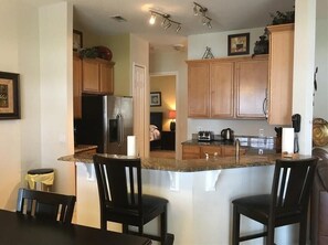 A kitchen with wooden cabinets, a granite countertop, and a refrigerator.