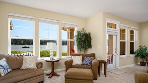 A living room with a view of a lake, beige walls, and two sofas with decorative pillows. - Happy Place at the Beach (Port Ludlow)
