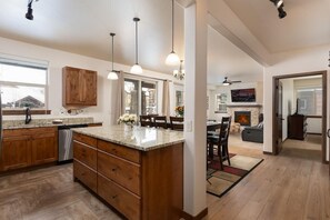 Una cocina amplia con armarios de madera, encimera de granito e iluminación colgante.