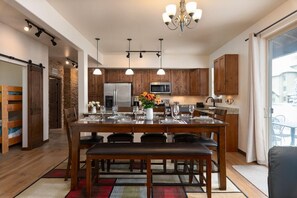 Una cocina moderna con armarios de madera, electrodomésticos de acero inoxidable y un comedor con una mesa preparada para cuatro.