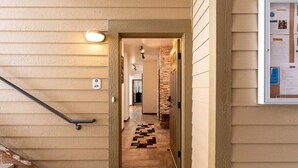 Un couloir avec un plancher en bois, un paillasson, une main courante et un tableau d’affichage au mur.