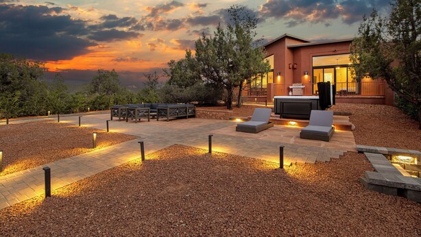 Eine Außenpatio mit Sitzgelegenheiten und Pool, umgeben von Bäumen und Blick auf den Sonnenuntergang.
