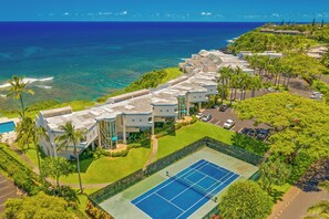 A resort with a tennis court, pool, and ocean views.